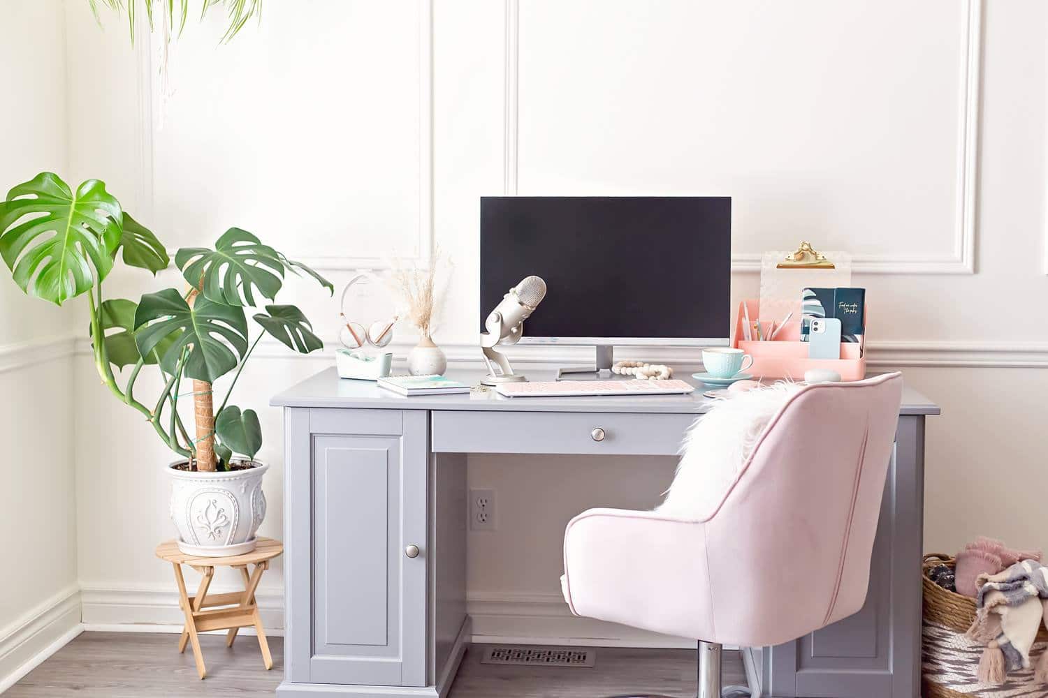 Feminine home office with a computer, pink chair and a podcast microphone