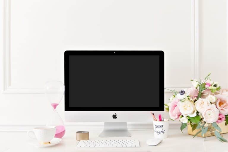 iMac on a white desk with tea and flowers