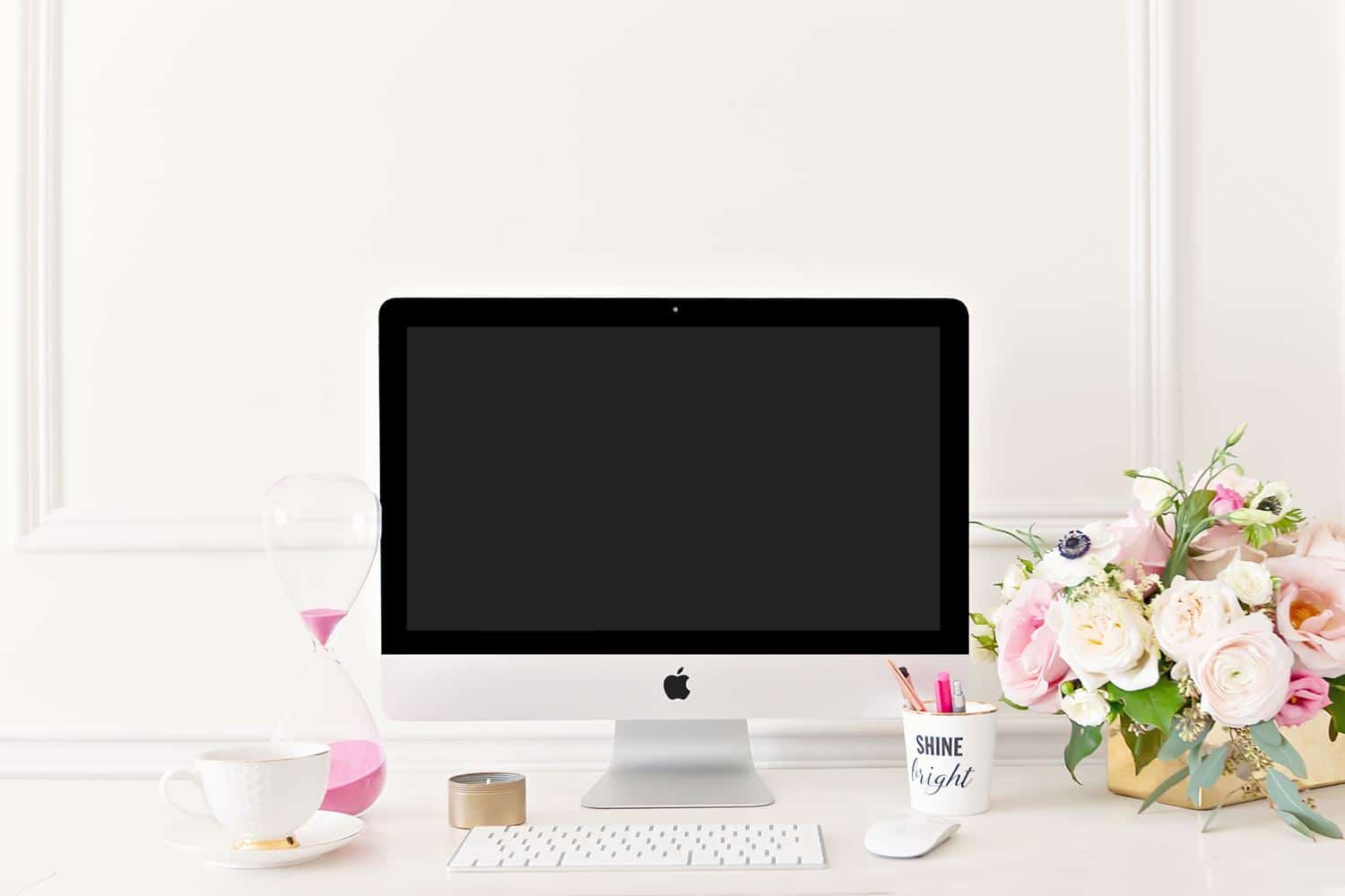 iMac on a white desk with tea and flowers