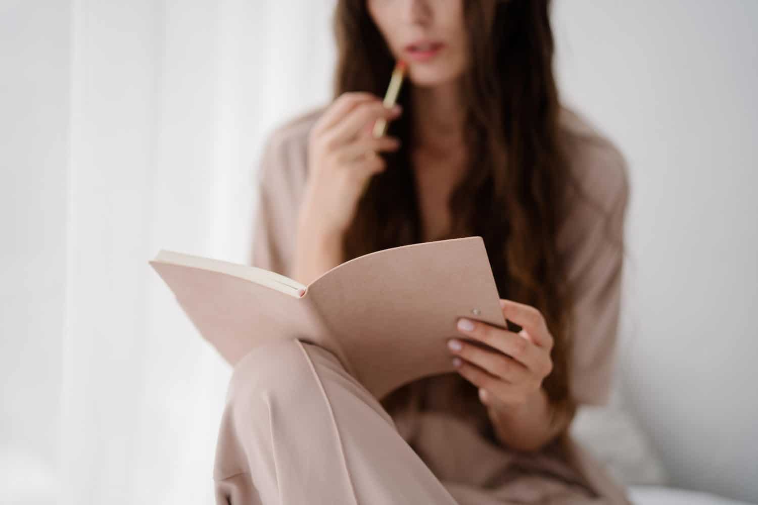 Woman looking at her notebook thoughtfully with a pen in her hand