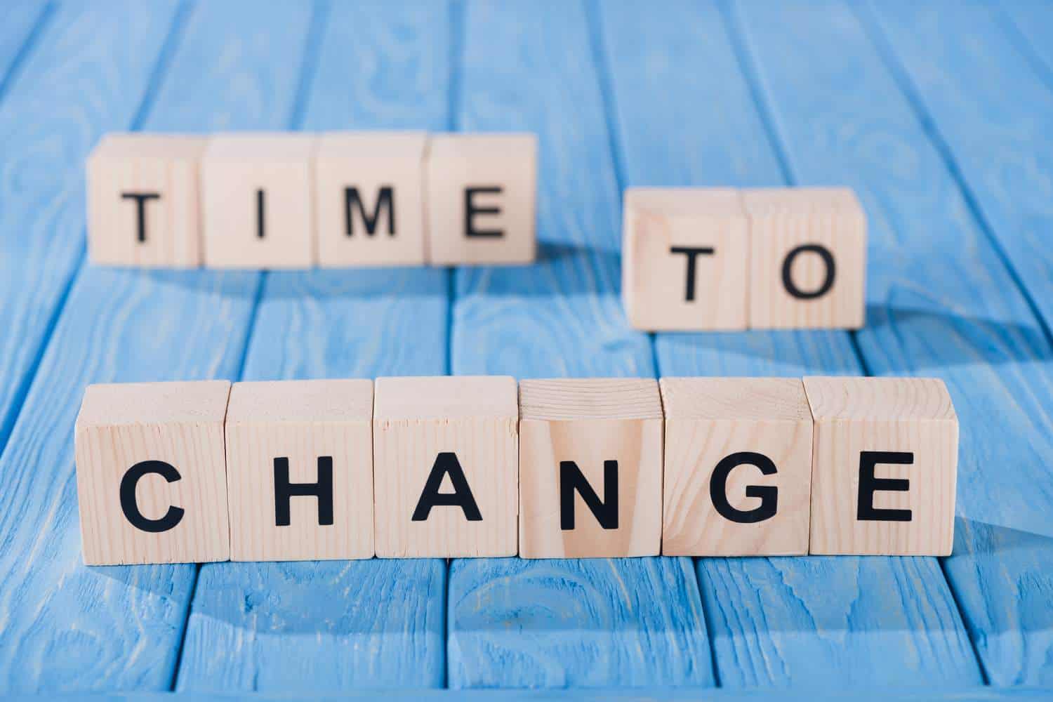 Wooden blocks that say time to change on blue wooden boards