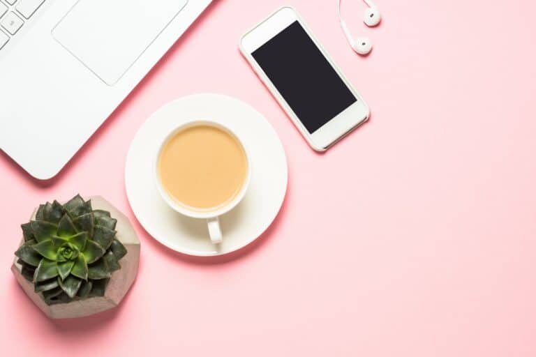 Laptop, phone, tea cup and a succulent on a pink background