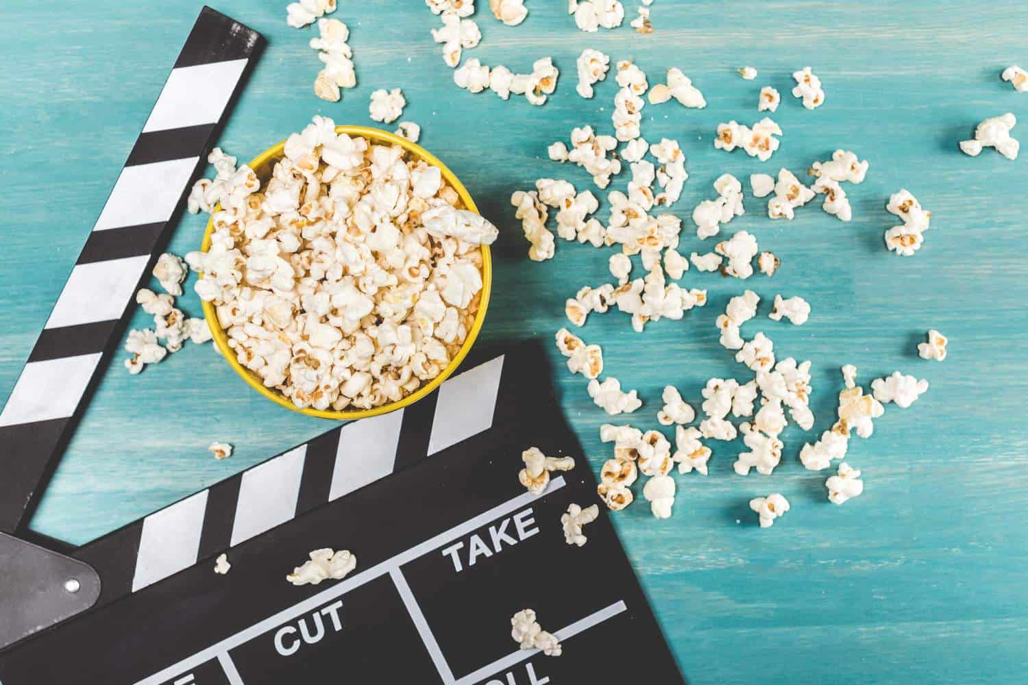 Movie popcorn and a clapper on a turquoise painted background