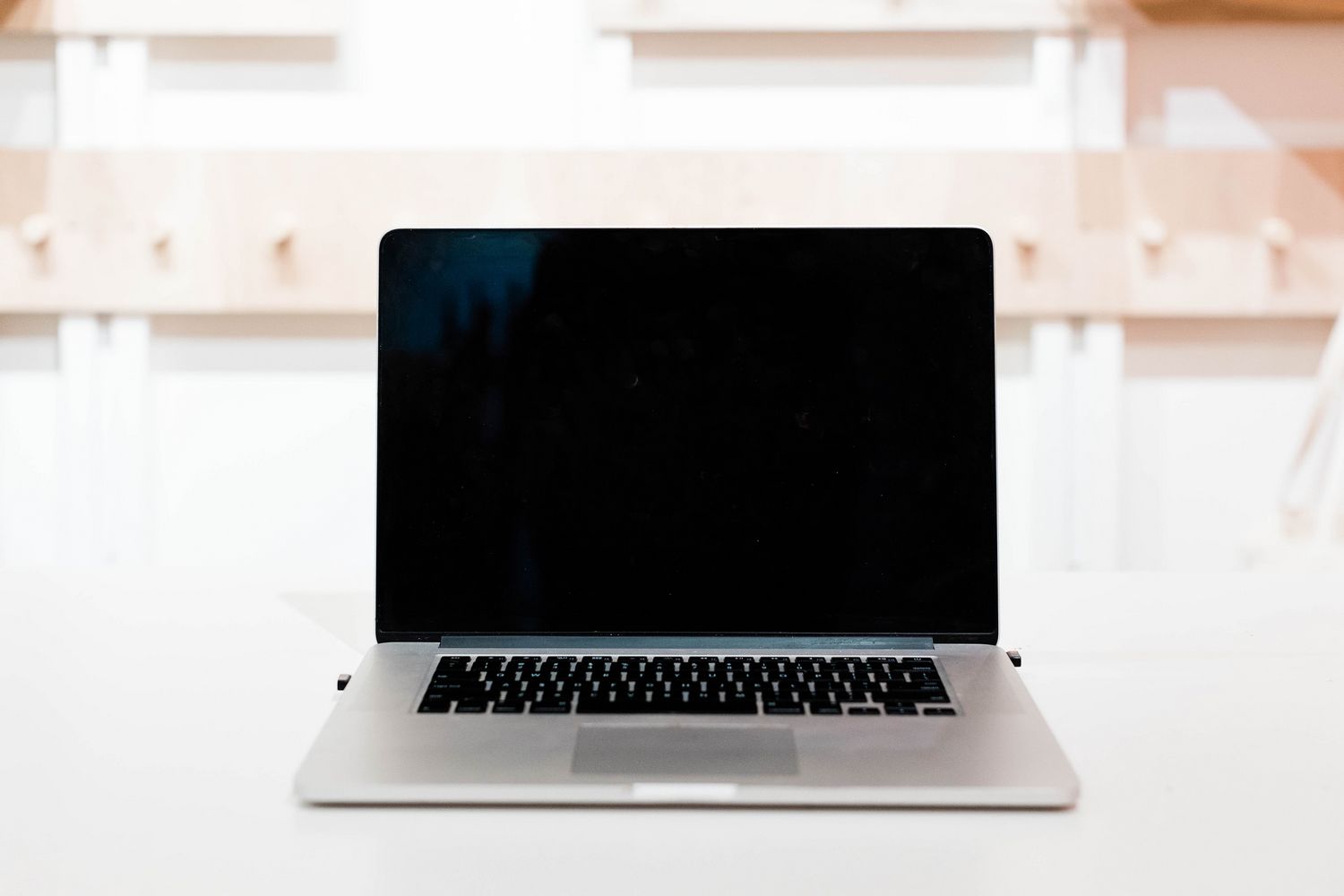 A Macbook that has been turned off on a white desk