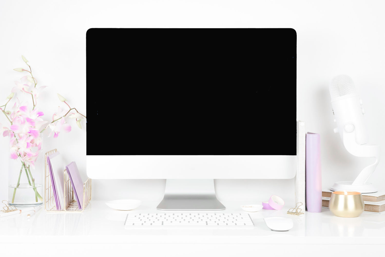 An iMac on a desk next to purple stationery