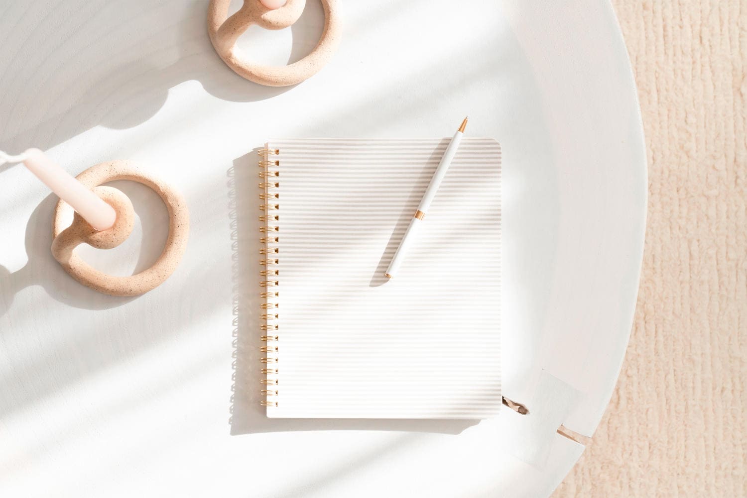 Candles and a white notebook and a pen on a desk