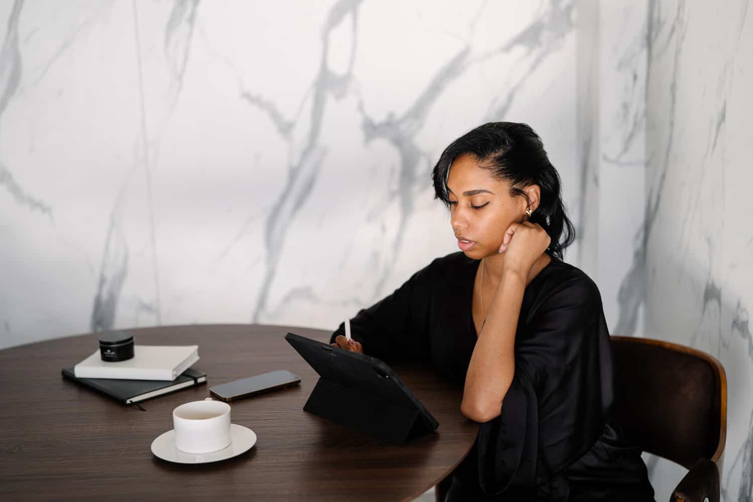 Woman sitting at a table and working on her tablet