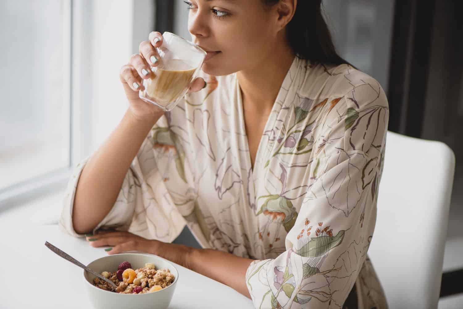 Woman sitting at breakfast table drinking coffee