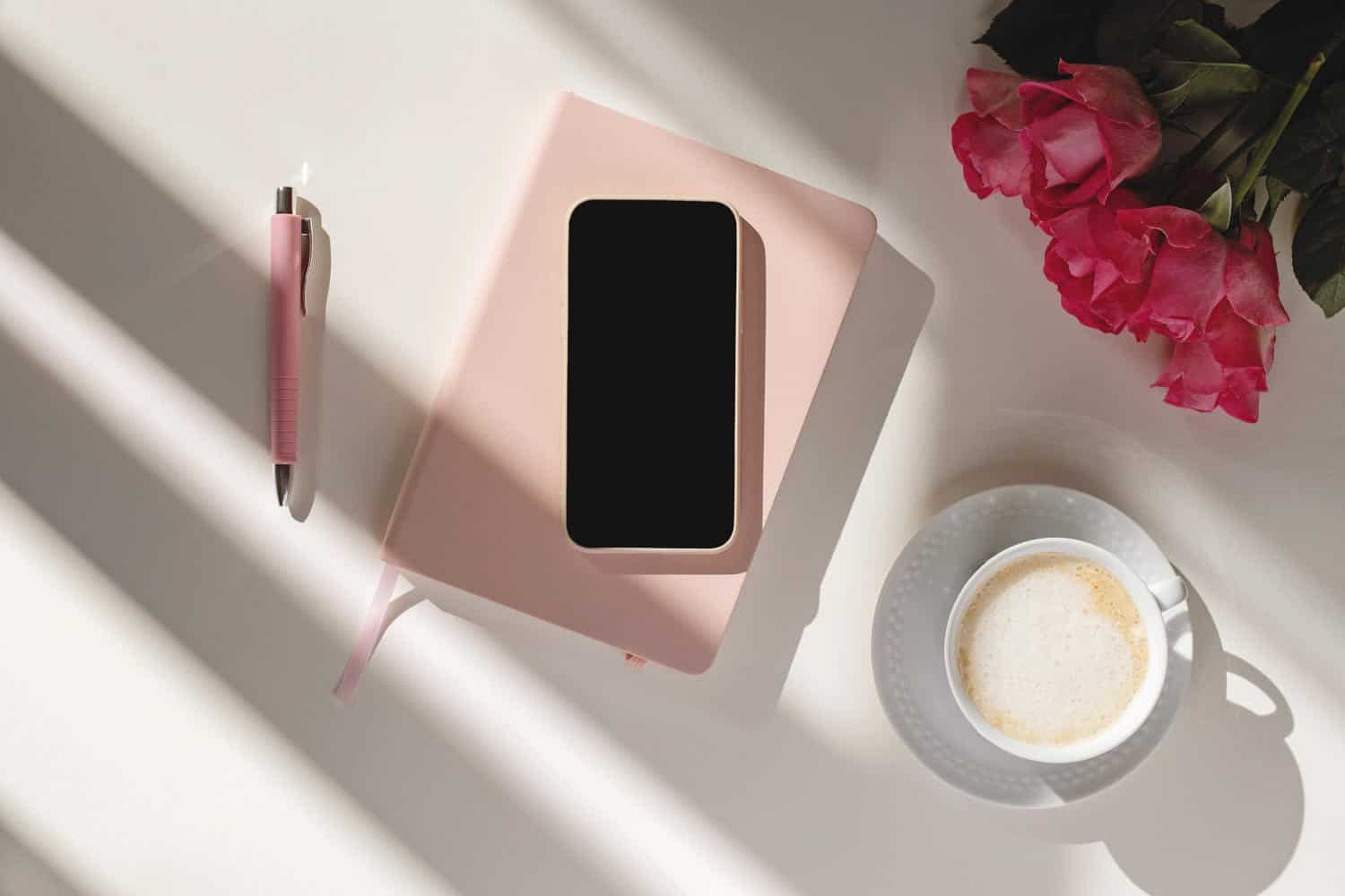 Pink notebook with a mobile phone on top of it