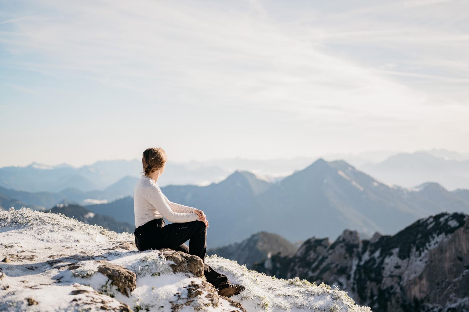 Woman sitting on a rock and looking at mountains