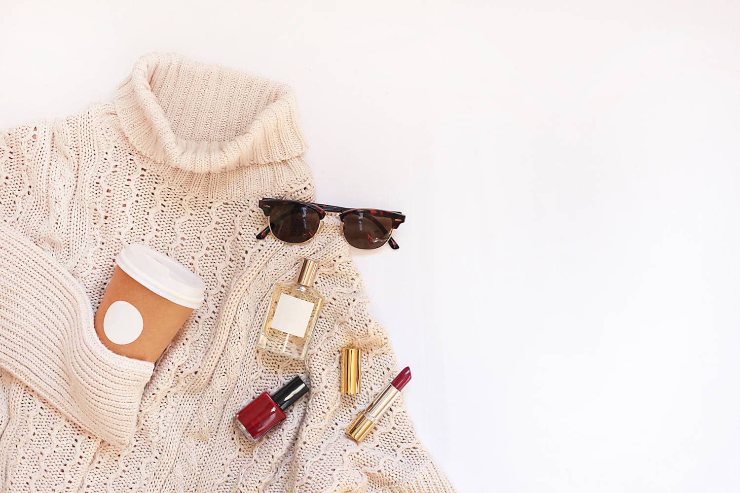 Beige sweater with makeup, sunglasses, and a coffee cup